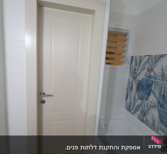 דלת לבנה עם ידית מתכת בחדר אמבטיה